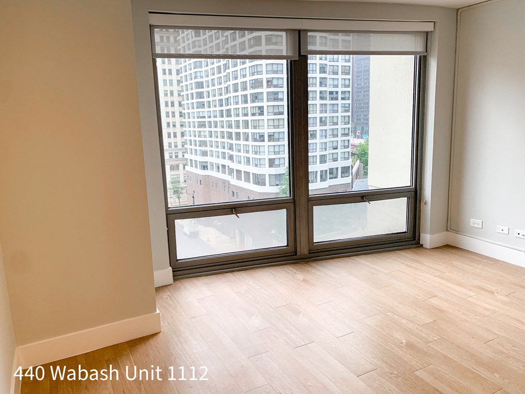 an empty living room with a large window and wooden floors
