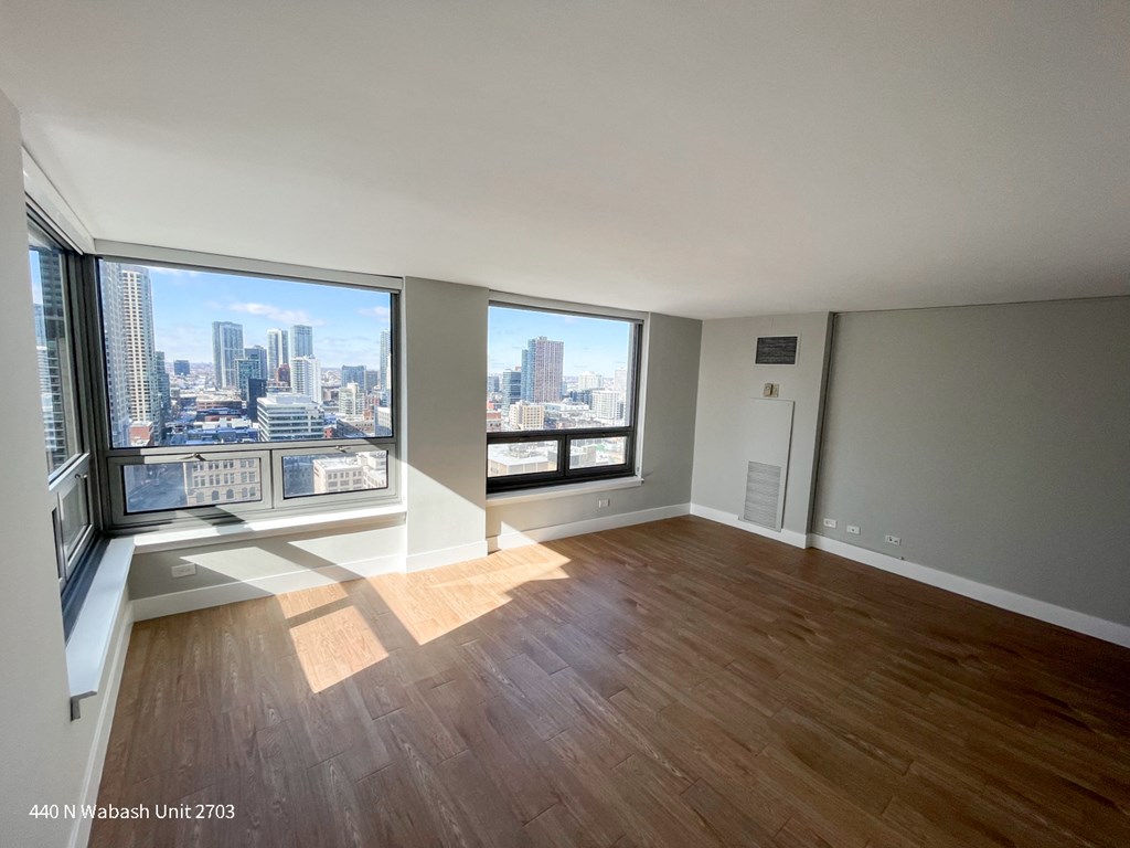 an empty living room with wood floors and a view of the city