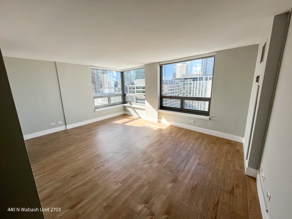 an empty living room with wood flooring and a large window
