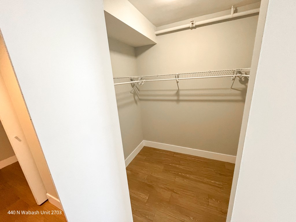 an empty closet with a wood floor and white walls