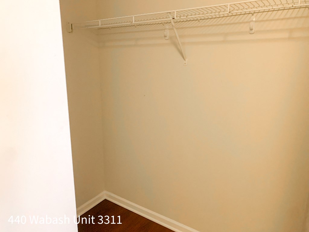 a room with a white wall and a closet with a rack on the wall