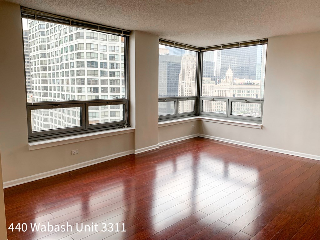 an empty living room with a wood floor and large windows