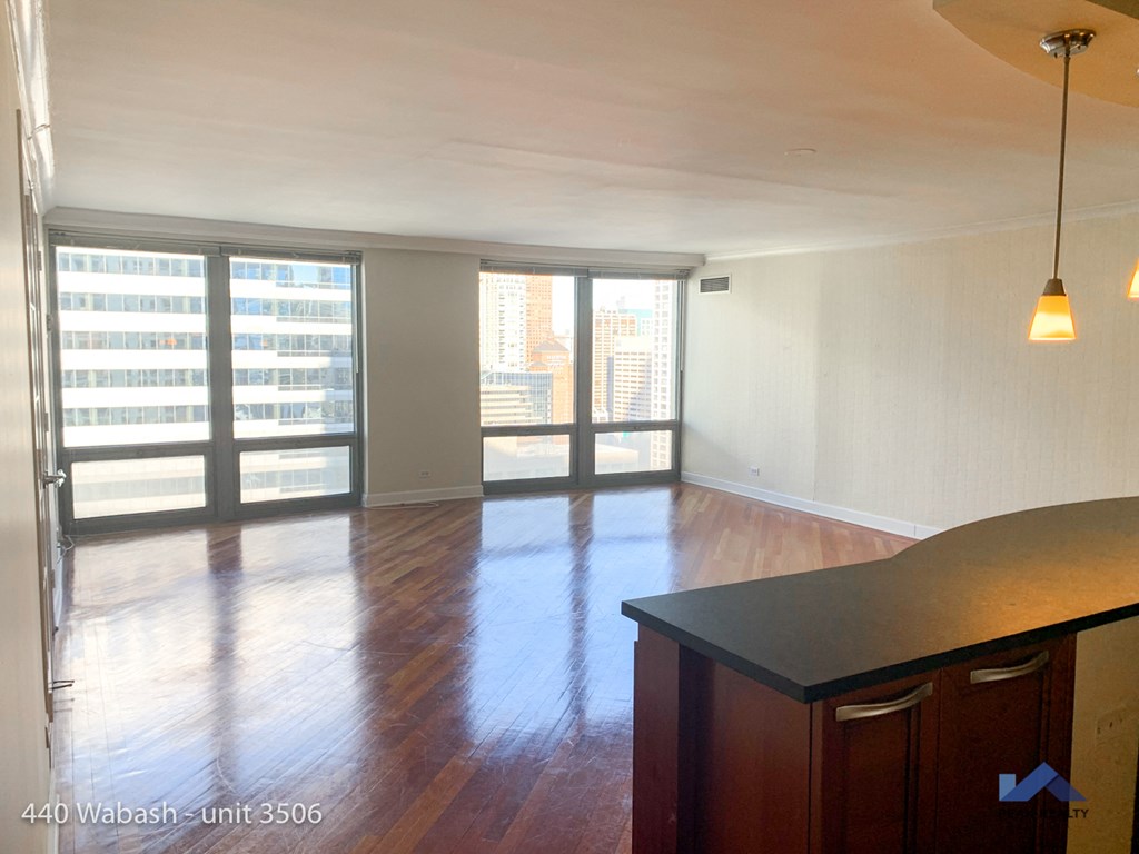 an empty living room with wood floors and a large window