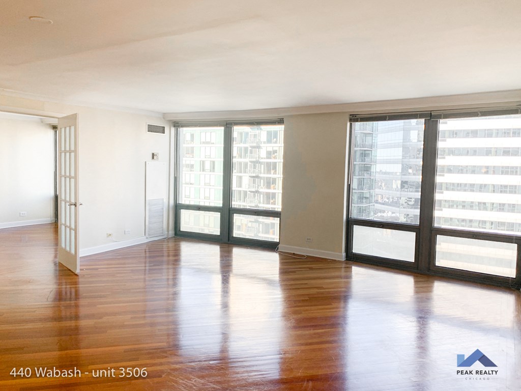 an empty living room with wood floors and large windows