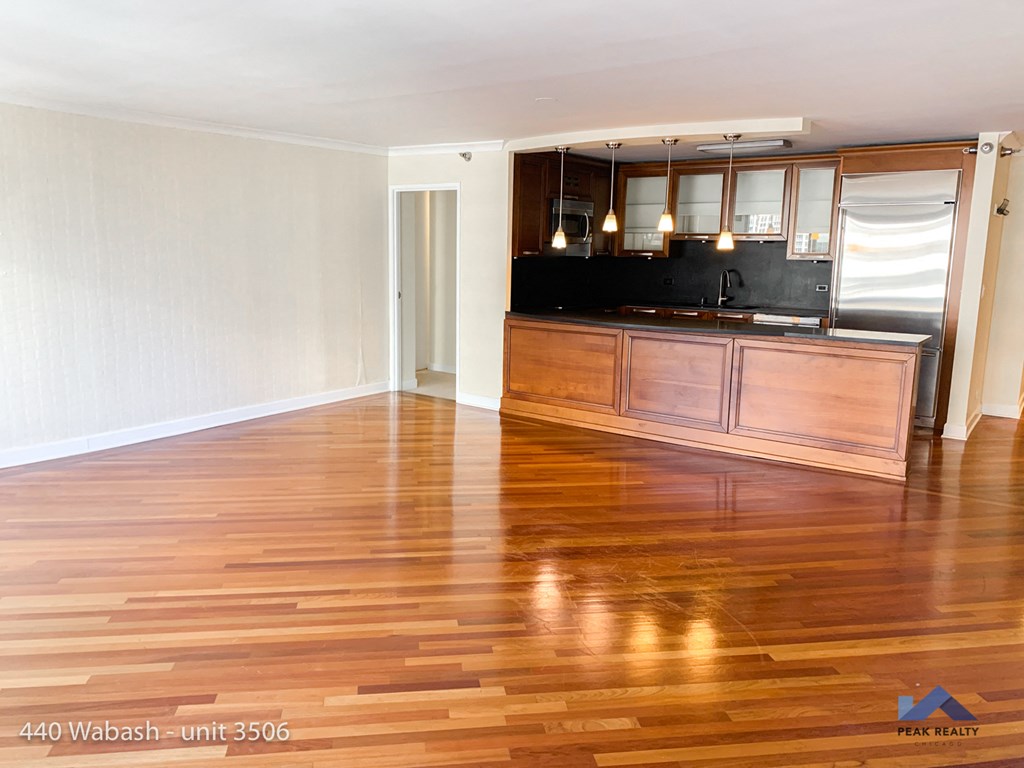 an empty living room with wooden floors and a kitchen