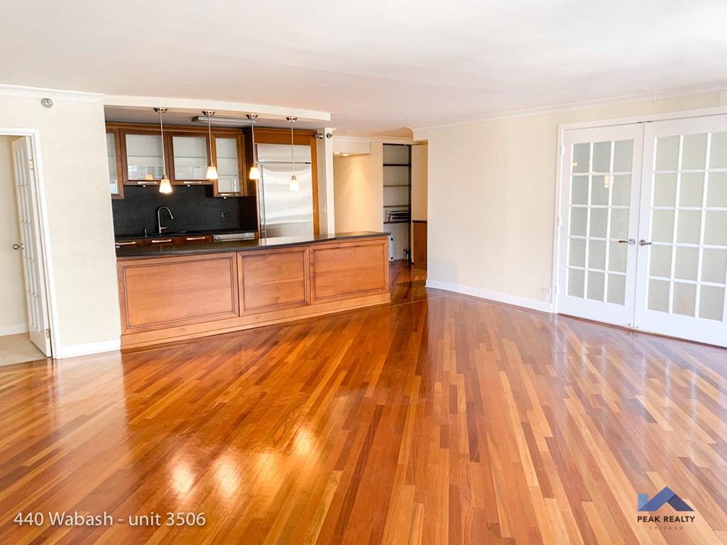 an empty living room with a wooden floor and a kitchen