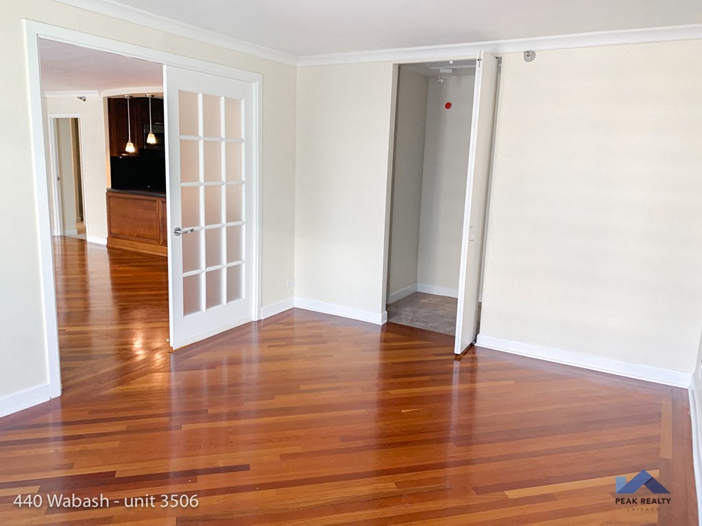 an empty living room with wood floors and an open door