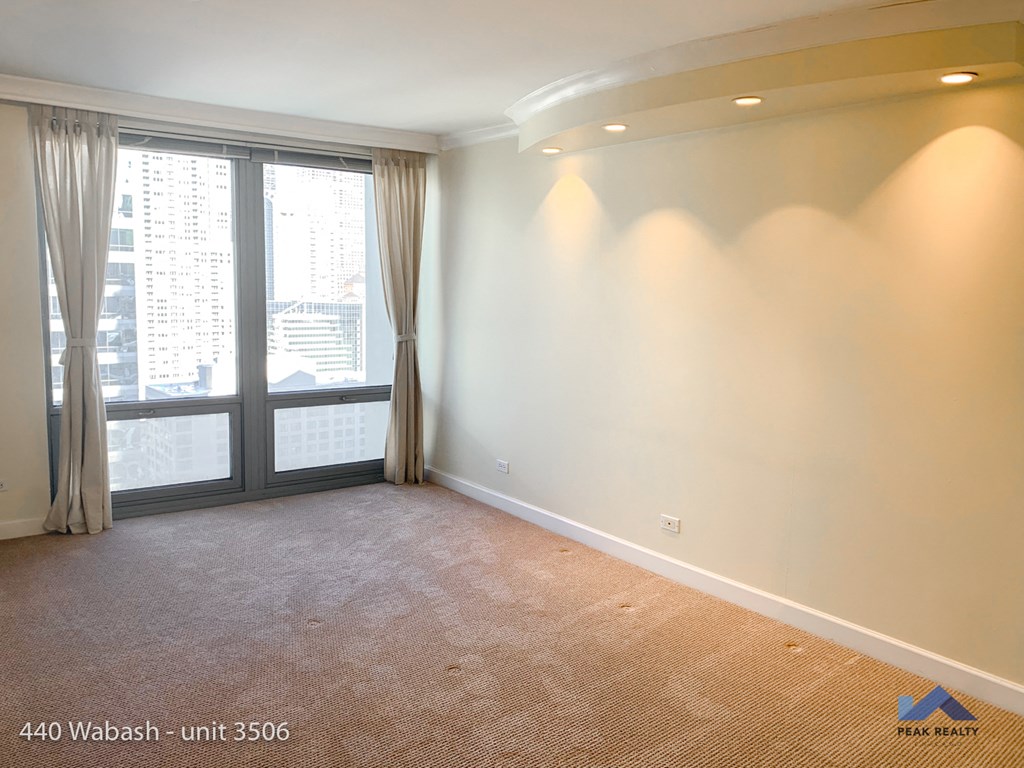 an empty living room with a large window and white walls