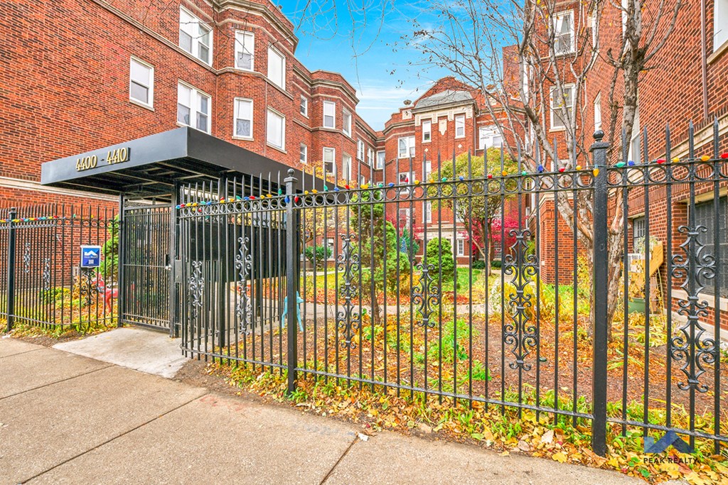 a wrought iron fence in front of a yard behind a apartment building