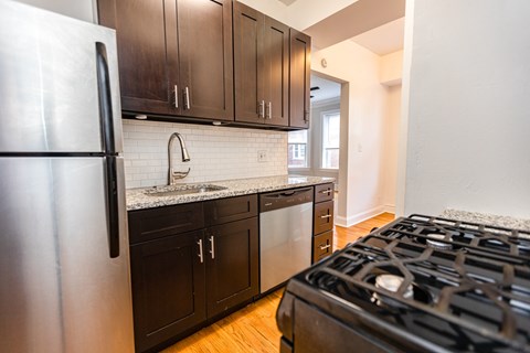 A modern kitchen with a stainless steel refrigerator and black cabinets.