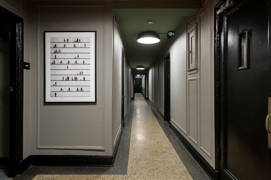 a hallway with black doors and a poster of shoes on the wall
