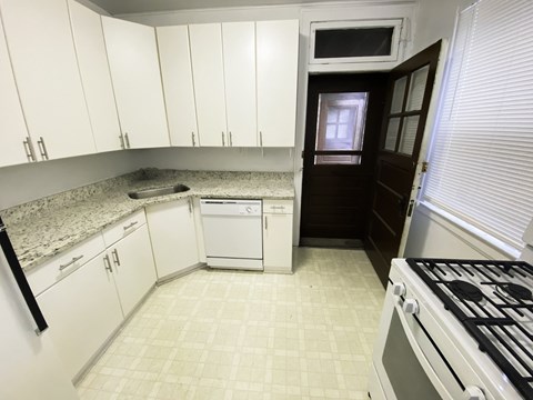 A kitchen with white cabinets and a black fridge.