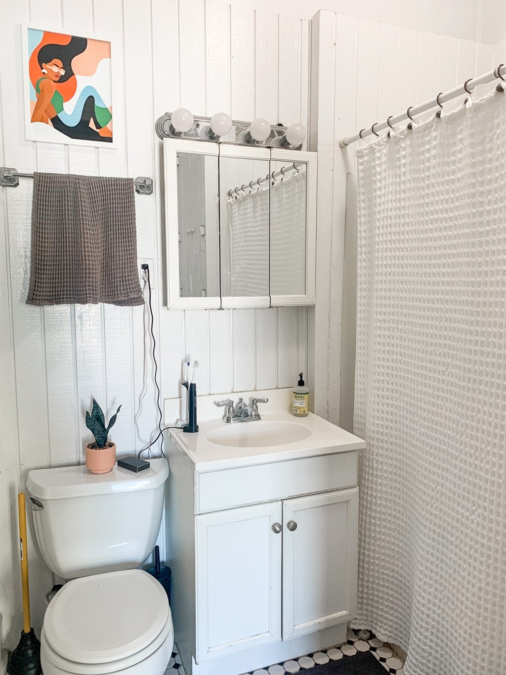 A white bathroom with a toilet, sink, and shower curtain.