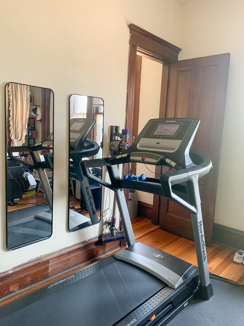 A treadmill is in a room with a mirror on the wall.