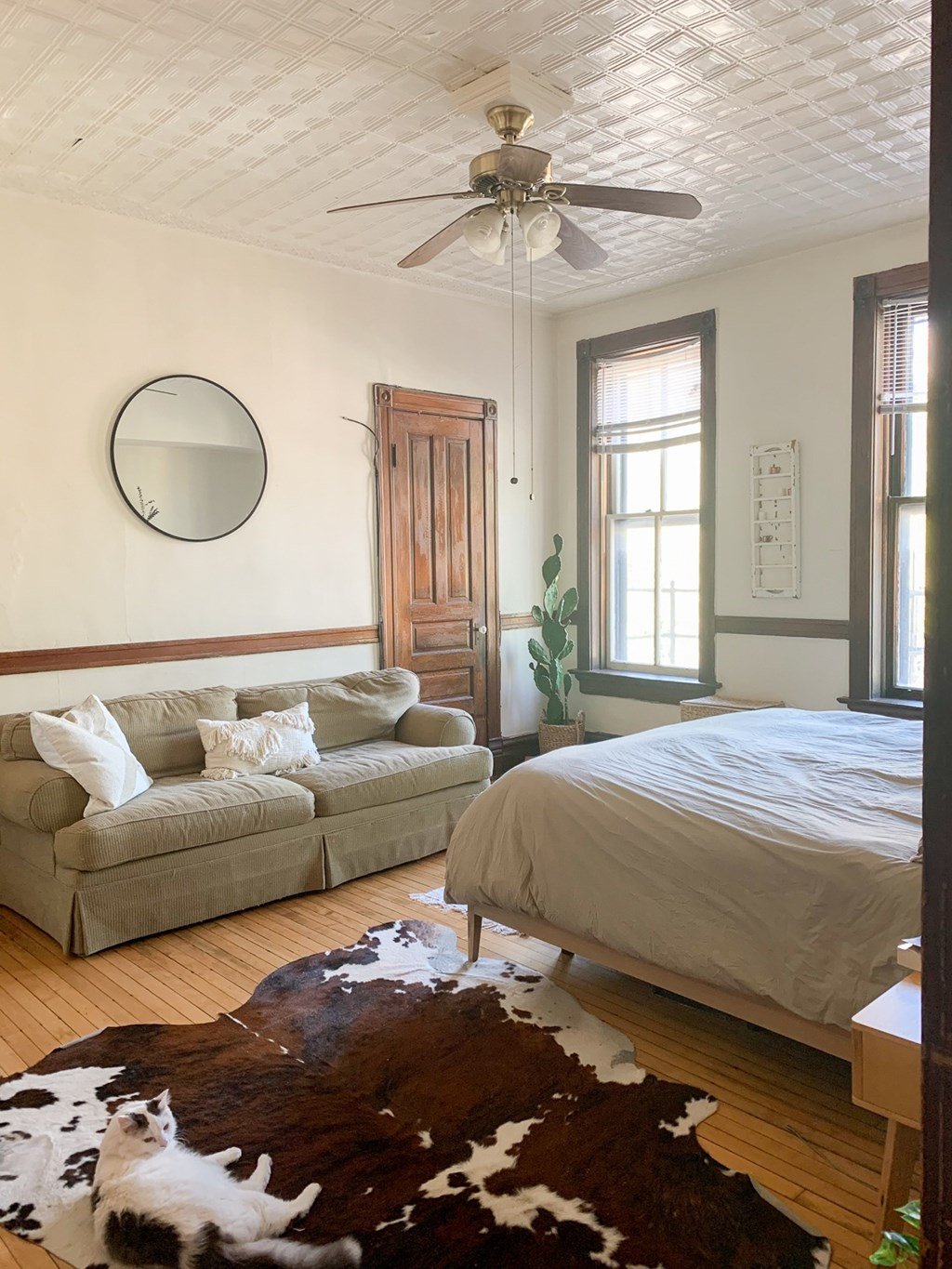A bedroom with a bed, couch, and cowhide rug.