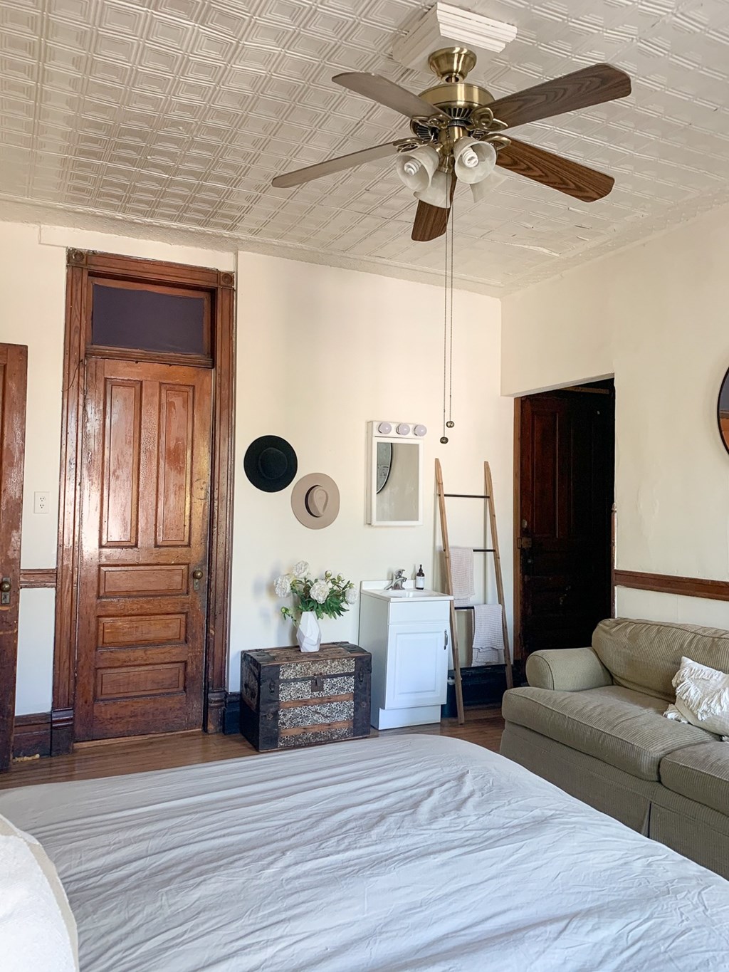A bedroom with a bed, a couch, a dresser, and a ceiling fan.