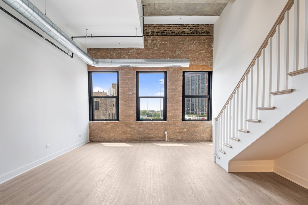 A large empty room with a staircase on the right side.