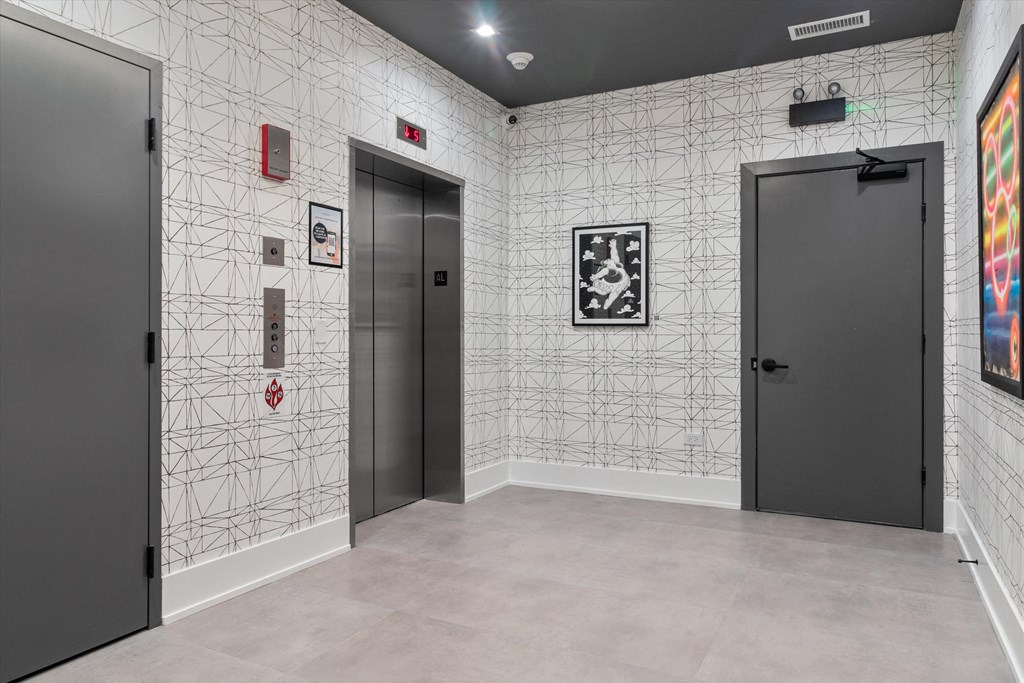 a hallway with two elevators and a wall covered in a patterned wall paper