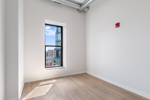 A room with a window showing a view of a building outside.
