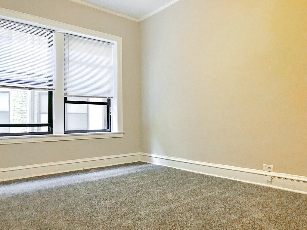 an empty room with two windows and a carpet