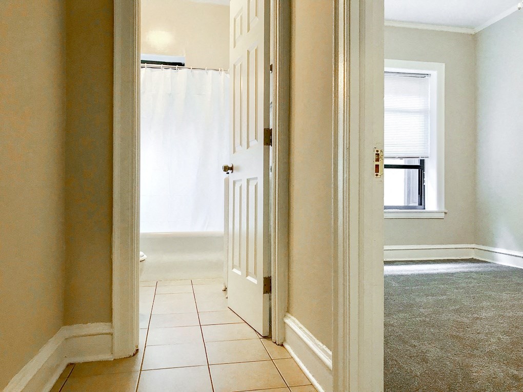 a hallway with a door to a bathroom and a white shower curtain