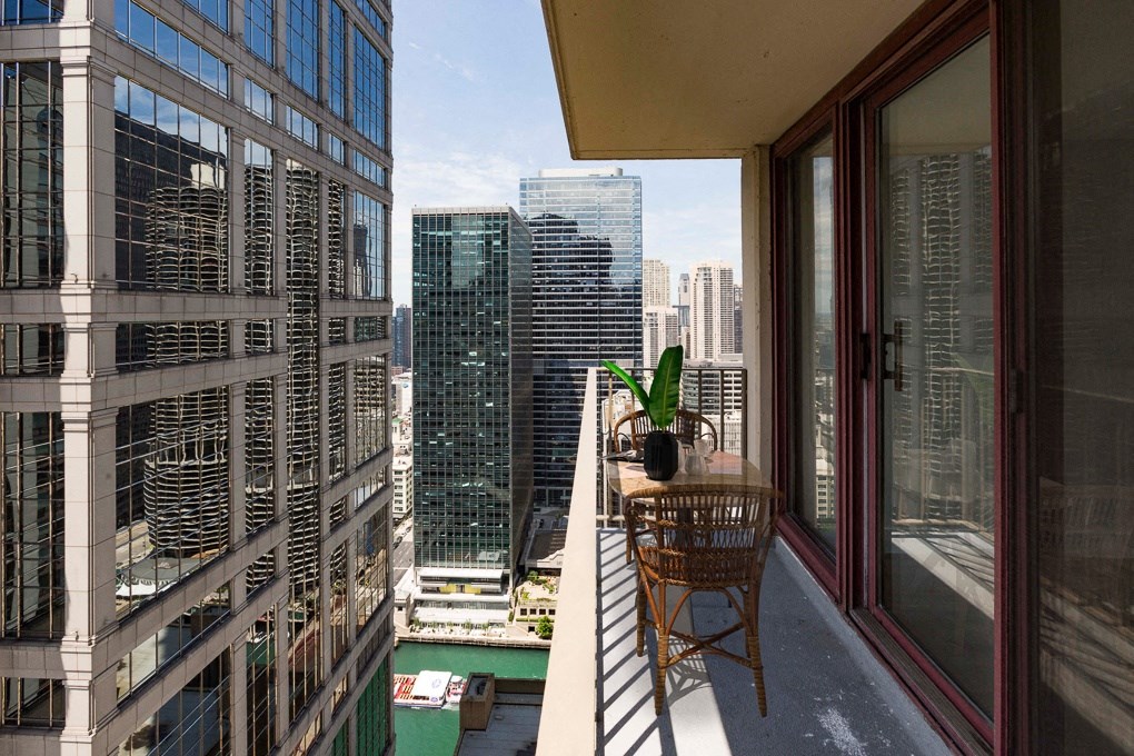 a view of the city from a balcony with a chair and a plant