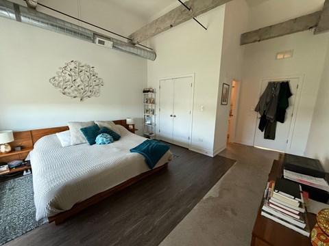 A bedroom with a large bed and a wooden floor.