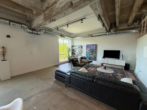 A living room with a black leather couch and a television.