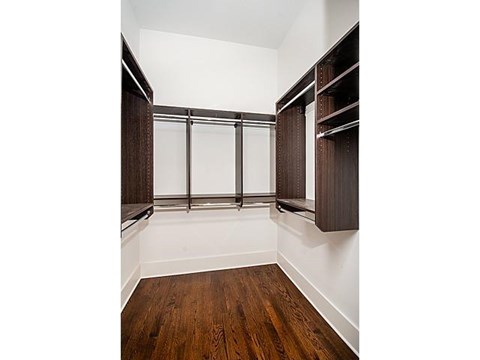 A room with a wood floor and a wall of shelves.