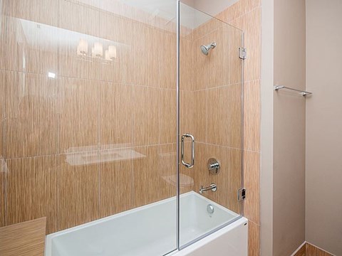 A modern bathroom with a glass shower door and a white bathtub.