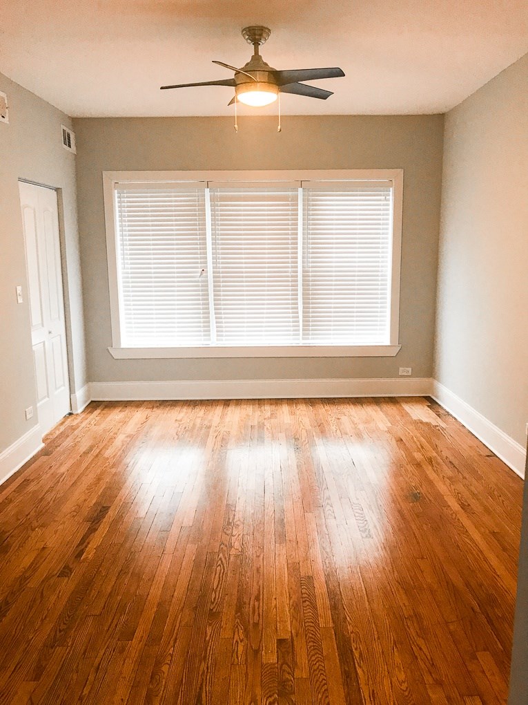 an empty living room with wood floors and a ceiling fan