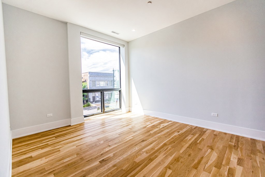 an empty living room with wood flooring and a balcony