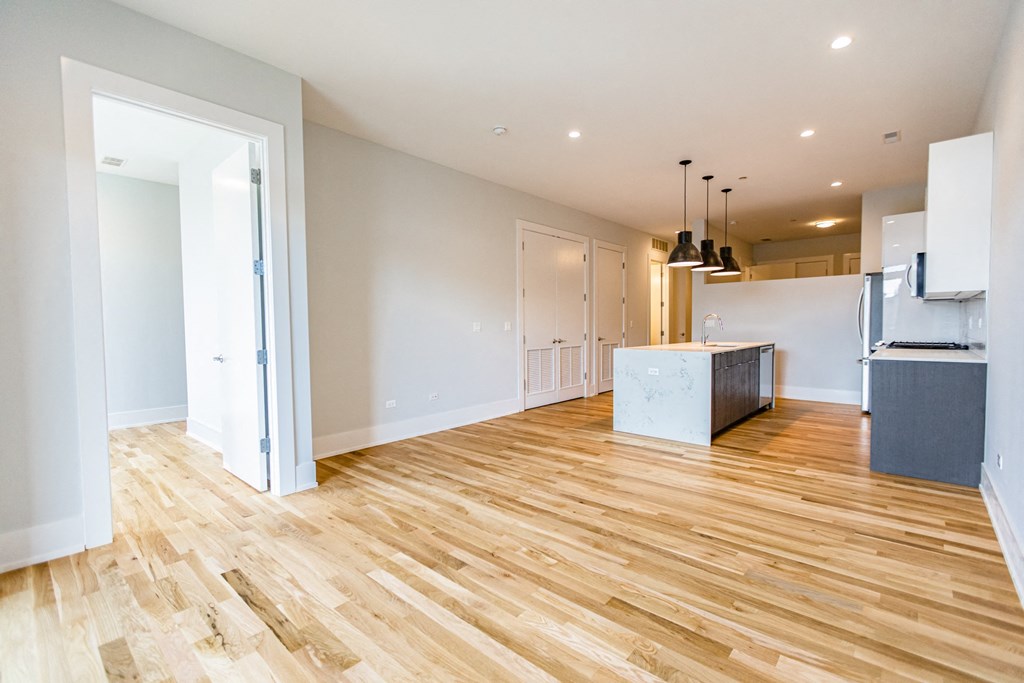 a living room and kitchen with wood flooring and white walls