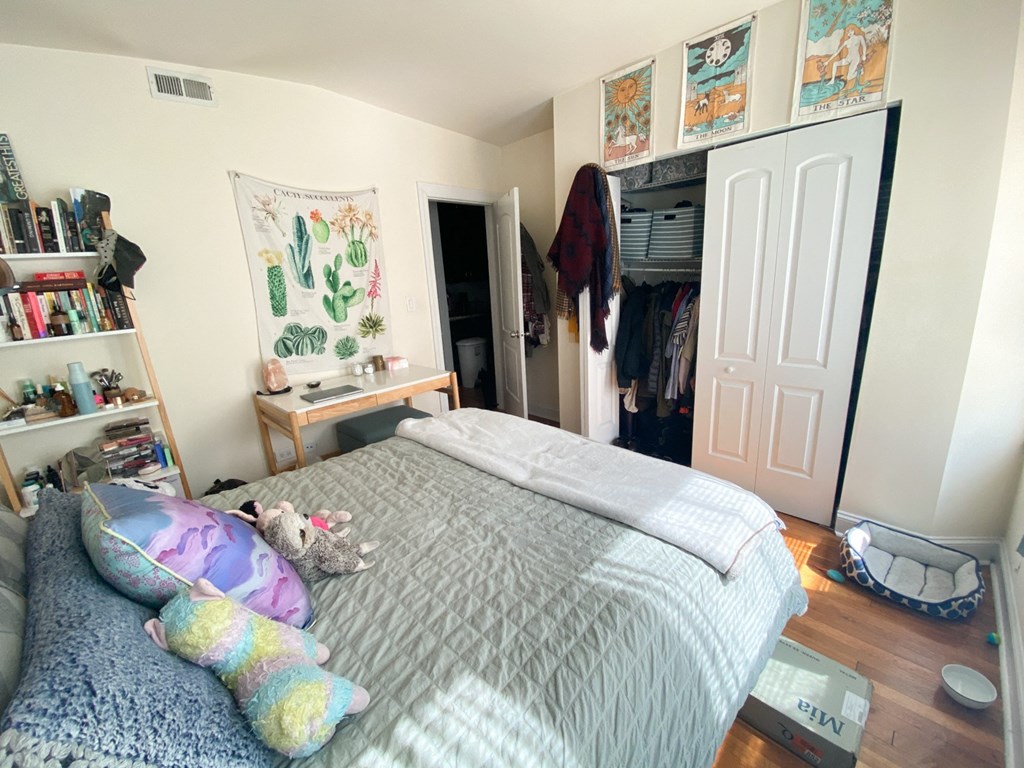 a bedroom with a bed and a closet with clothes in it