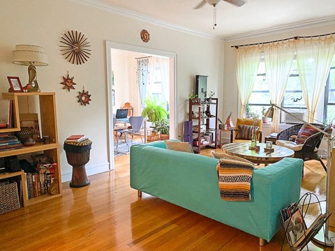 A living room with a green couch and a wooden floor.