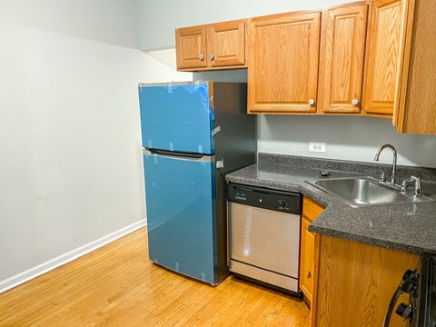 A kitchen with a blue fridge and wooden cabinets.