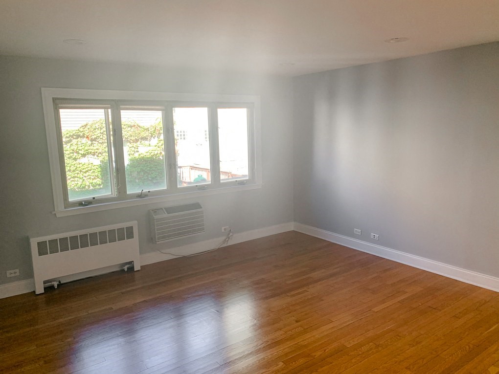 an empty living room with a wooden floor and a window
