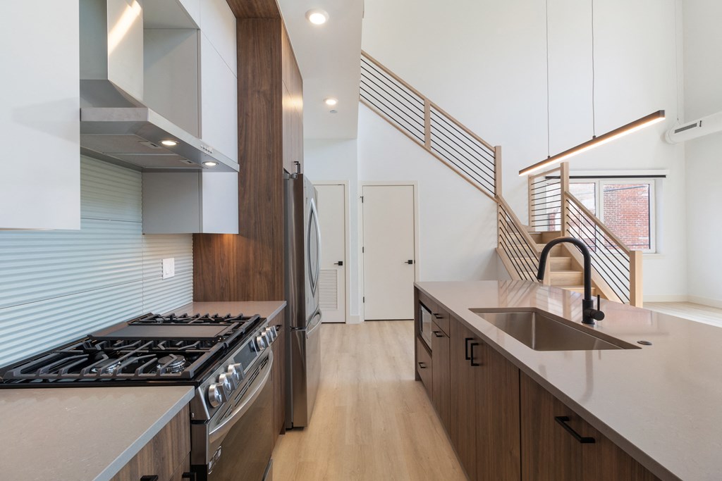 a kitchen with a stove and a sink and a staircase