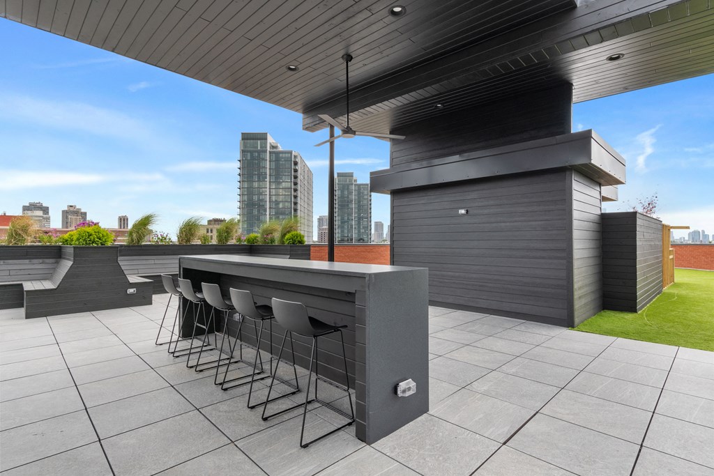 a bar area on the roof of a building with a view of the city in the background