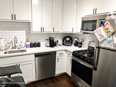 A kitchen with white cabinets and a variety of appliances and cookware.
