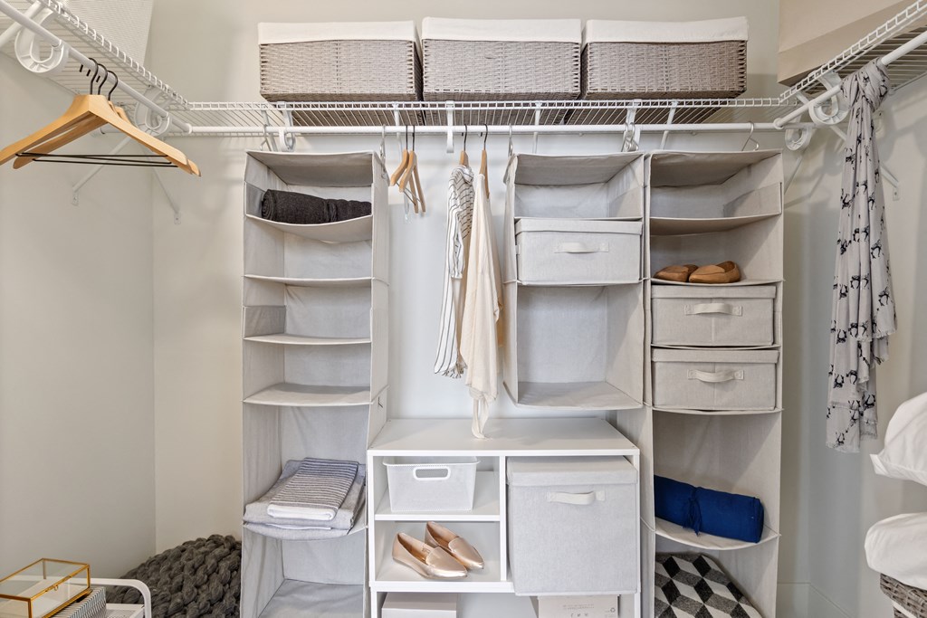 a walk in closet with white shelves and drawers