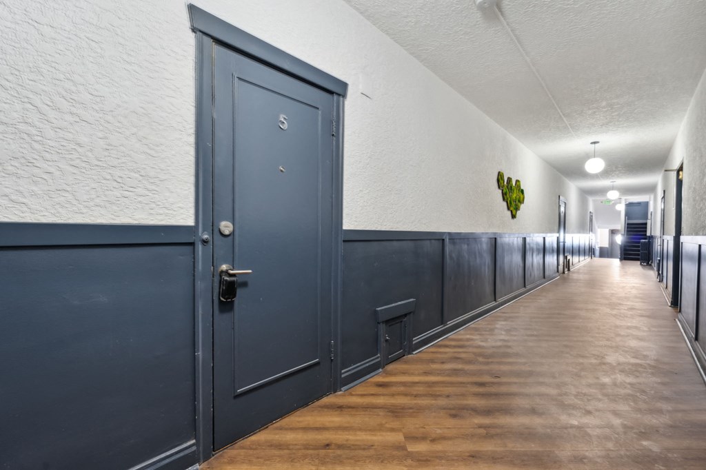a hallway with blue doors and white walls and a wood floor