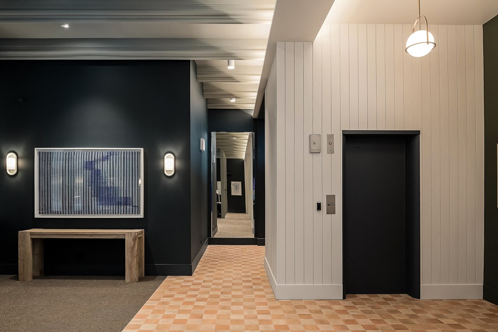 a hallway with black walls and a checkered tile floor and a black door
