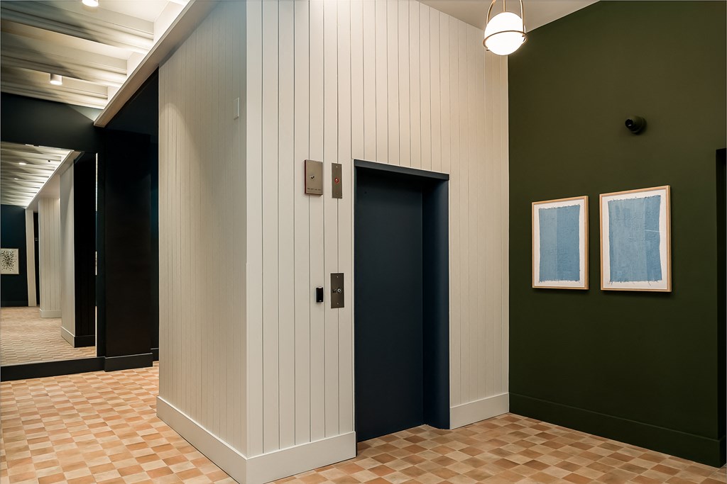 a hallway with a door and two paintings on the wall