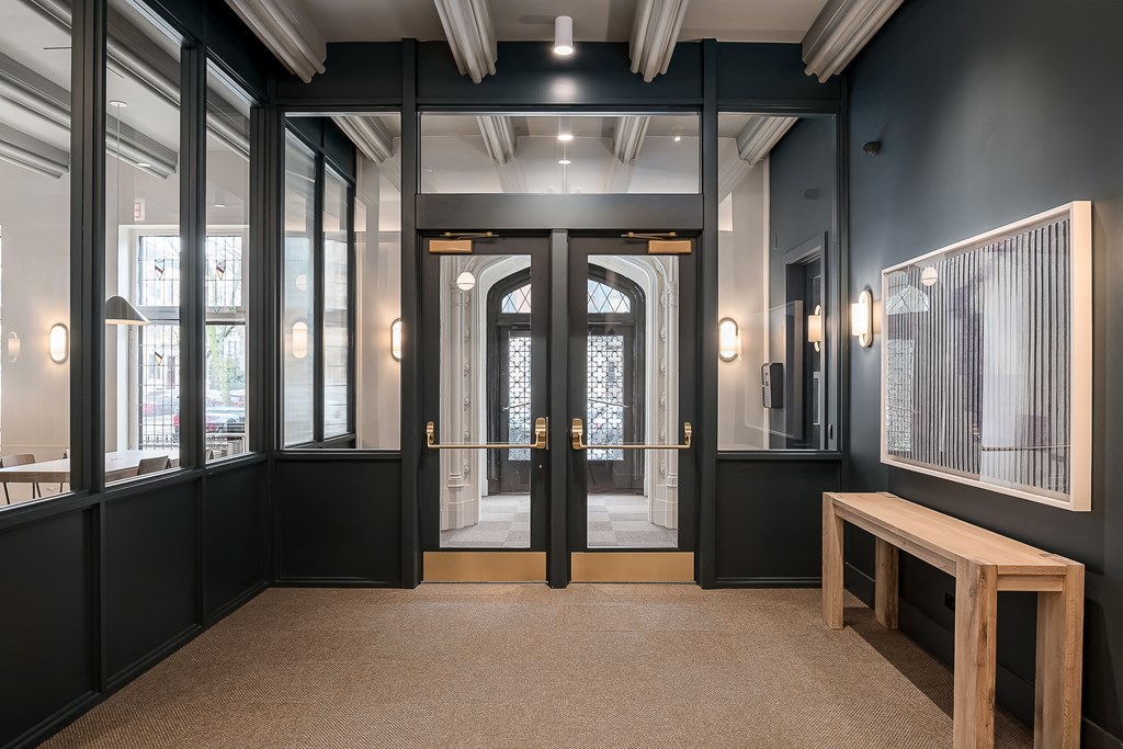 a lobby with black walls and doors and a wooden bench