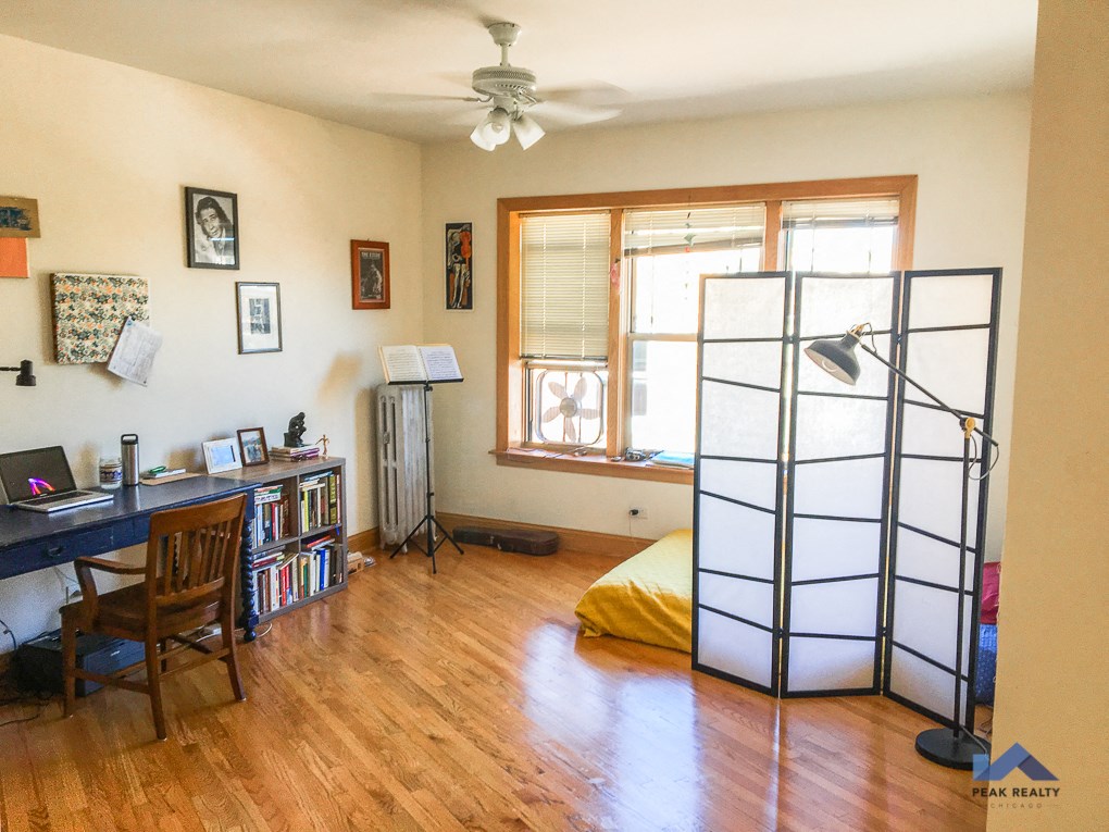 an empty room with a bed and a desk and a ceiling fan