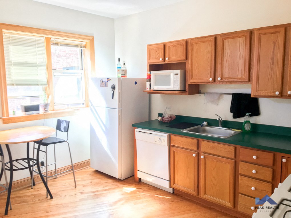 a kitchen with green countertops and wooden cabinets and a white refrigerator