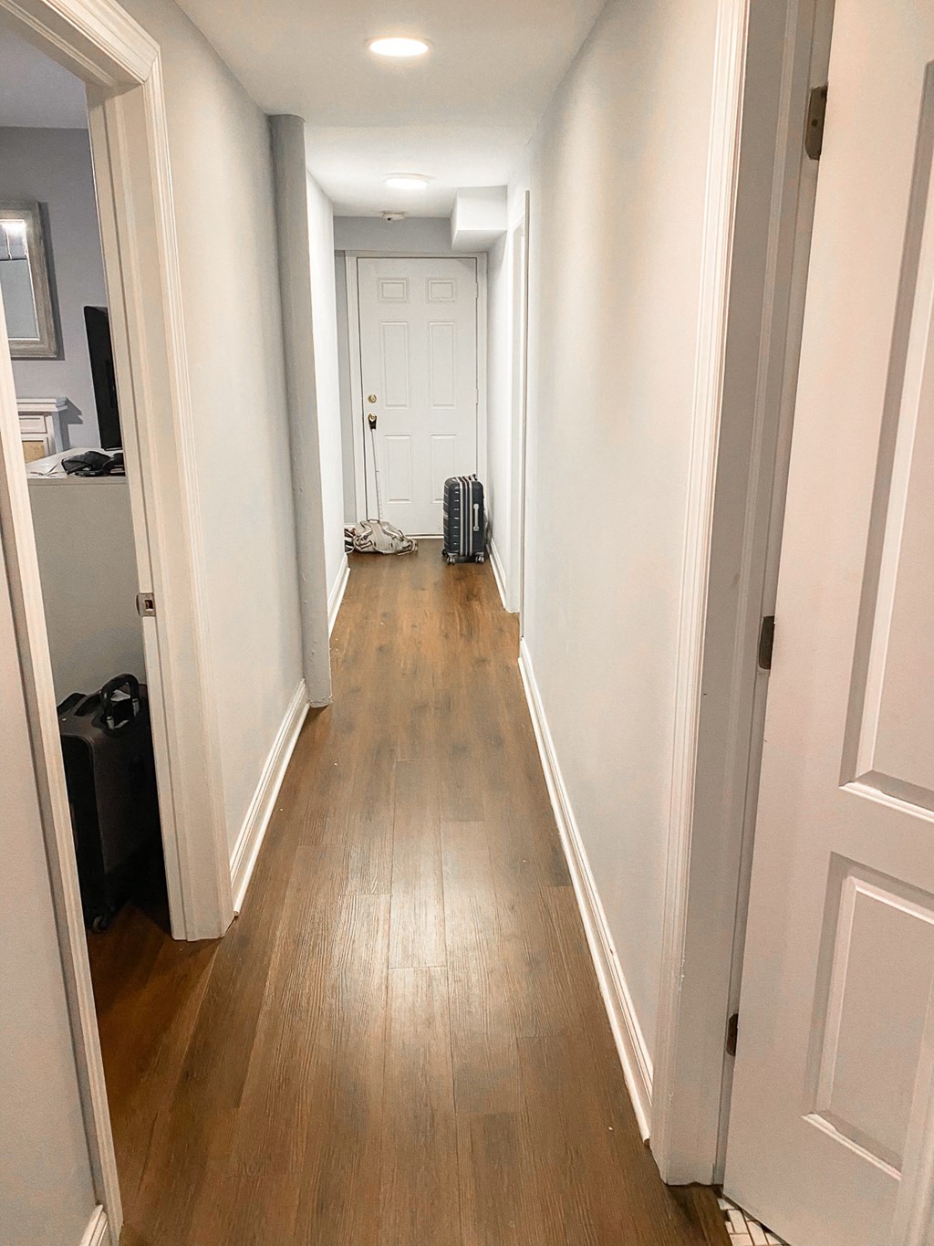 a hallway with wood floors and white walls and a white door