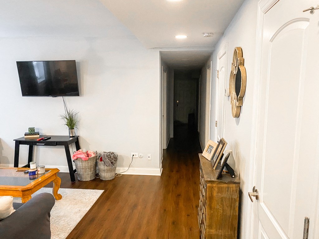 a living room with a tv on the wall and a hallway to another room