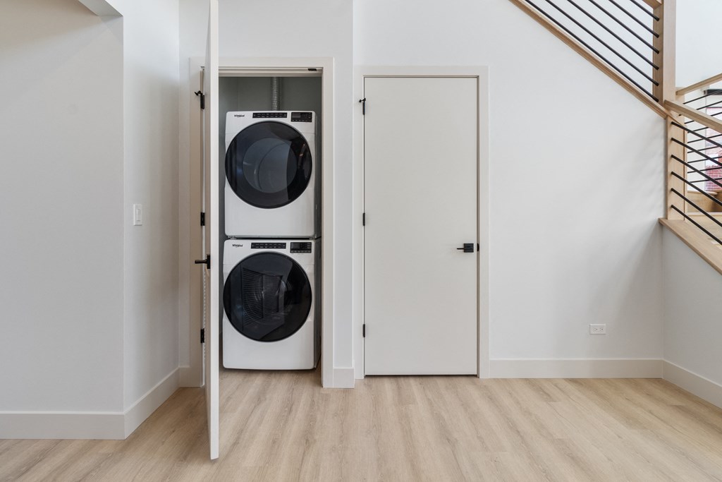 a front loading washer and dryer in a white room with a white door
